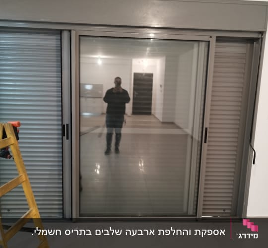 תריסים אפורים סגורים ליד חלון זכוכית גדול